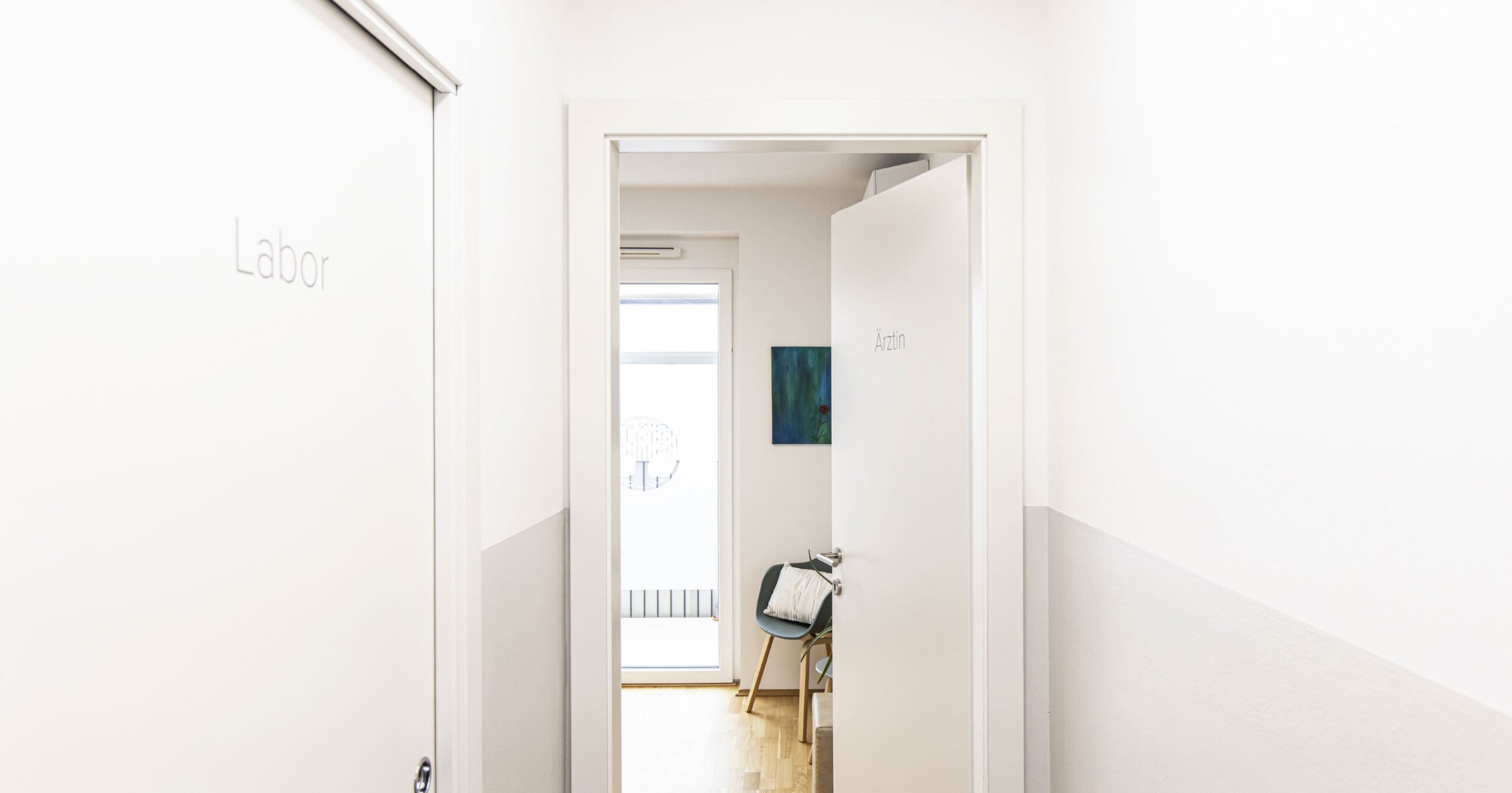 Blick aus dem Vorraum in ein Behandlungszimmer, links ist eine verschlossene Tür mit der Aufschrift 